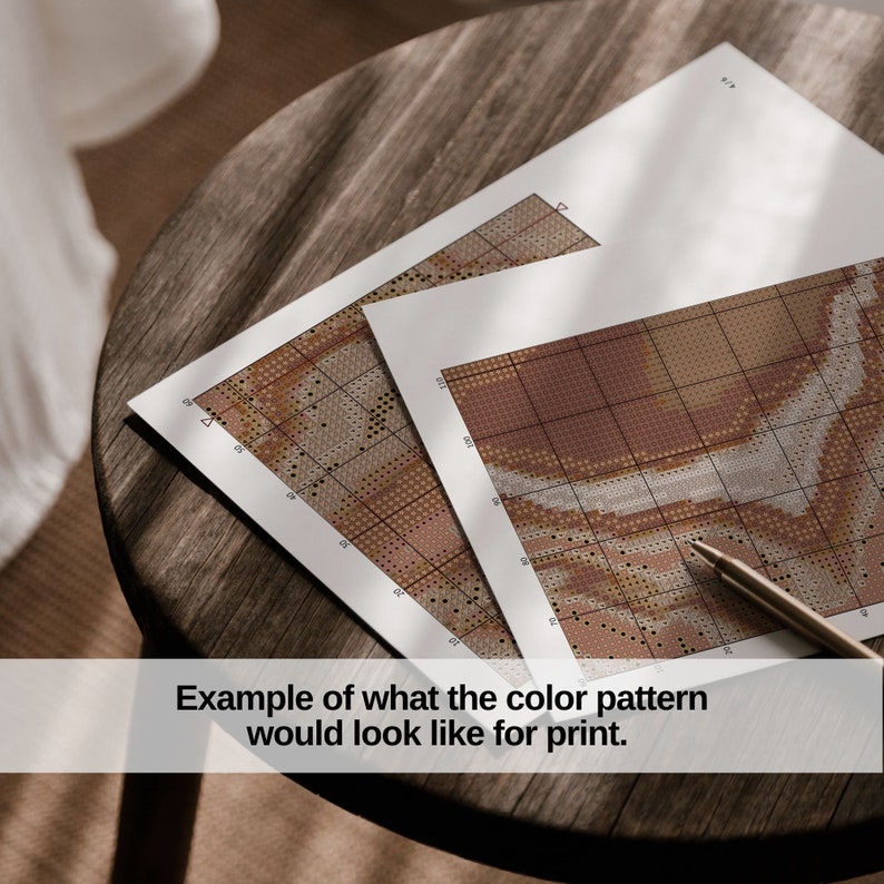 May include: Two cross-stitch pattern sheets with a pen on a wooden table. The patterns display a colour palette of browns, tans, and creams. The image text reads: "Example of what the colour pattern would look like for print."