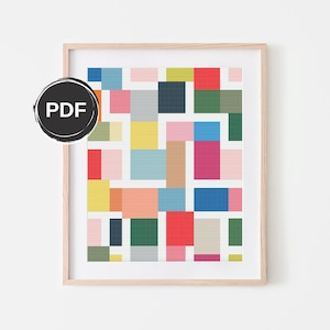 Puede incluir: Un patrón de punto de cruz geométrico colorido con cuadrados en tonos de rosa, rojo, azul, verde, amarillo y naranja. El patrón está enmarcado en un marco de madera claro.