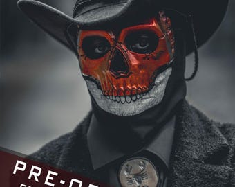 May include: A black cowboy hat with a silver skull emblem, a red and grey skull mask, and a bolo tie featuring a scorpion pendant. The attire includes a black collared shirt and a textured black coat. Text on the image reads: PRE-ORDER FOR JULY.