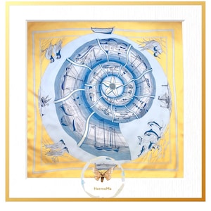 Può includere: Una sciarpa di seta incorniciata con un design nautico. La sciarpa presenta un motivo a spirale blu e bianco con barche e vita marina. Il bordo è dorato e la cornice è bianca. Il testo "HermeMa" si trova in basso a destra.