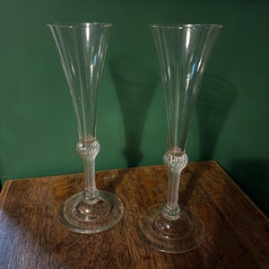 May include: Two clear glass champagne flutes with a twisted stem and a wide base.