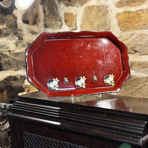 May include: A red octagonal serving tray with a black rim and a white and black floral design. The tray is on a dark wood surface.