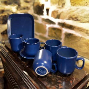 May include: A set of blue ceramic mugs and a creamer with a matching blue saucer. The mugs and creamer have a smooth, glossy finish.