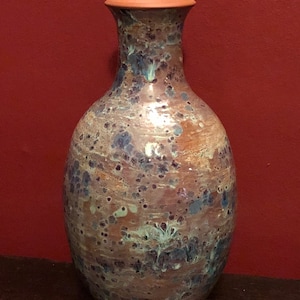 May include: A ceramic vase with a mottled brown, blue and white glaze. The vase has a narrow neck and a wide, rounded body.