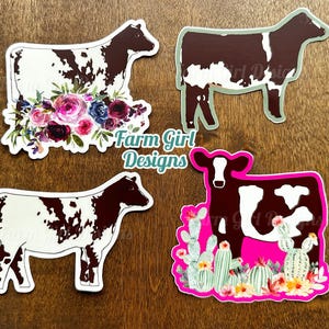 May include: Four different cow stickers with a white and brown spotted pattern. The stickers are on a wooden surface. The stickers have different backgrounds, including flowers, cacti, and a solid pink background. The stickers are all approximately 3 inches in size.