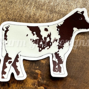 May include: A white and brown cow sticker with a spotted pattern. The cow is facing to the right and has a white background.
