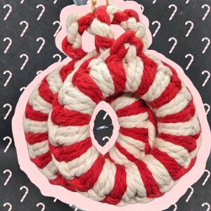 Op de afbeelding: Rode en witte gestreepte touw oorbellen. Het touw is gedraaid in een cirkelvorm met een kleinere cirkel in het midden.