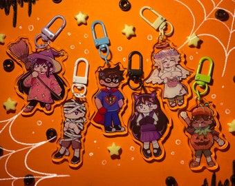Puede incluir: Ocho llaveros de personajes con temática de Halloween con diferentes diseños. Los personajes incluyen una bruja, una momia, un superhéroe, un gato, un ángel, una calabaza y dos más. Cada llavero tiene un anillo de metal para sujetarlo a una bolsa u otro artículo.