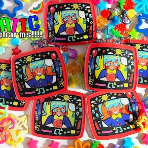 May include: Red-framed charms featuring a cartoon character with blue hair and a yellow bow tie, set against a black background with musical notes and numbers. The word "STATIC charms!!!!" is displayed in a pixelated font. Assorted colorful charms surround the main objects.