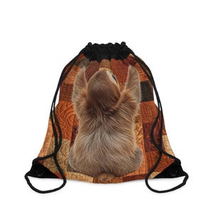 May include: Drawstring bag with a brown sloth design, arms raised. The background is a patchwork quilt in brown and orange hues. The bag has black drawstrings and a black top. The bag is suitable for carrying items.