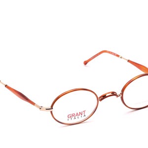 Op de afbeelding: Ovale bril met bruine montuur en goudkleurige accenten. De bril heeft een klassiek ontwerp met de tekst "GRANT ITALIA" op de lens.