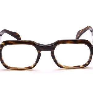 Può includere: Occhiali con montatura marrone scuro con motivo tartarugato. Le lenti quadrate sono trasparenti e le aste sono curve. Gli occhiali hanno uno stile classico e vintage, adatti all'uso quotidiano. La montatura è realizzata in materiale resistente.