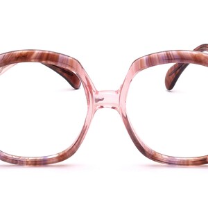 Könnte beinhalten: Eine Brille mit braunem und rosafarbenem Schildpattgestell in quadratischer Form.