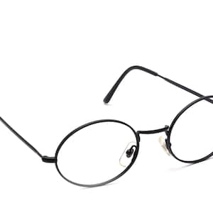以下が含まれることがあります： 黒い楕円形のフレームの眼鏡。 眼鏡は細い黒い金属フレームと透明なレンズを備えています。 耳にかける部分は快適なフィット感のためにわずかに湾曲しています。 眼鏡は白い背景に置かれています。