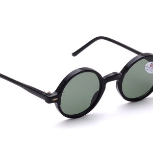Könnte beinhalten: Schwarze runde Sonnenbrille mit grünen Gläsern und einem UV-Schutz-Etikett auf dem rechten Glas.