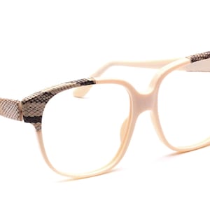 Op de afbeelding: Witte kunststof gemonteerde bril met een slangenhuidpatroon op de pootjes.