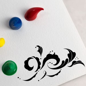 May include: Four paint colors in squeeze tubes, red, blue, yellow, and green, on a white surface with a black decorative design.