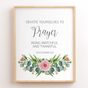 Pode incluir: Uma impressão emoldurada com fundo branco e um design floral na parte inferior. O texto diz "Dedique-se à oração, esteja vigilante e seja grato, Colossenses 4:2".