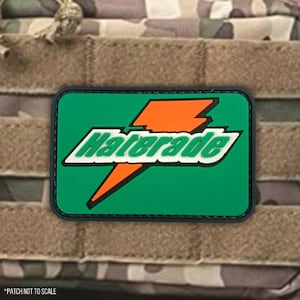 May include: A green and orange patch with the word "Haterade" in white letters. The patch has a black border and is designed to look like a sports drink logo.