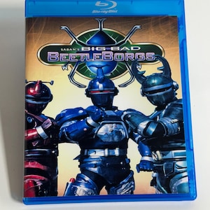 May include: A blue Blu-ray disc case featuring the title "Saban's Big Bad Beetleborgs." The cover art depicts three armored figures in red, blue, and teal, with a metallic insect-like design. The case has a blue border.