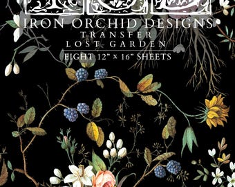 May include: A black background with a floral design featuring white, pink, yellow, and blue flowers. The text "IRON ORCHID DESIGNS TRANSFER LOST GARDEN EIGHT 12" x 16" SHEETS" is printed in white.