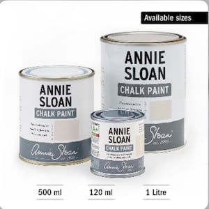 Może przedstawiać: Trzy puszki farby kredowej Annie Sloan w r&oacute;żnych rozmiarach: 120 ml, 500 ml i 1 litr. Puszki są białe z czarnym nadrukiem i logo Annie Sloan.