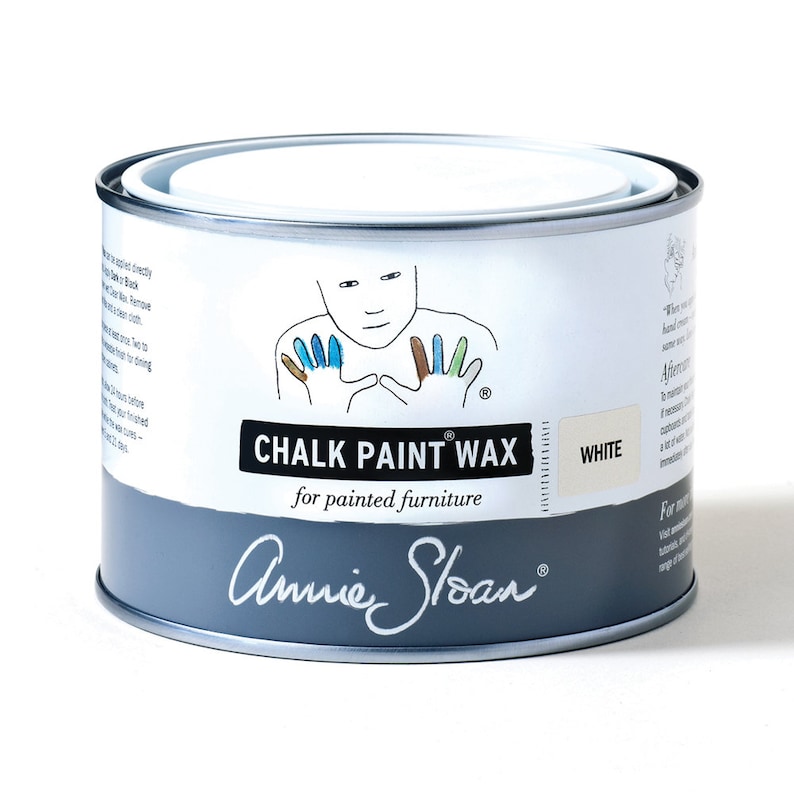 May include: A white can of Annie Sloan Chalk Paint Wax for painted furniture. The can has a hand-painted design of a person with colorful hands. The text on the can reads "Chalk Paint Wax" and "for painted furniture".