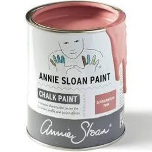 May include: A can of Annie Sloan Chalk Paint in the color 'Scandinavian Pink'. The paint is a light pink color and is shown with a small amount of paint dripping down the side of the can.