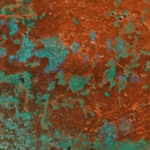 May include: Close-up of a textured surface with a mix of orange and teal green colors. The surface has a mottled, aged appearance.