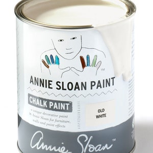 May include: A white can of Annie Sloan Chalk Paint in the color Old White. The can features a hand-painted illustration of a person with colorful hands and the brand name.