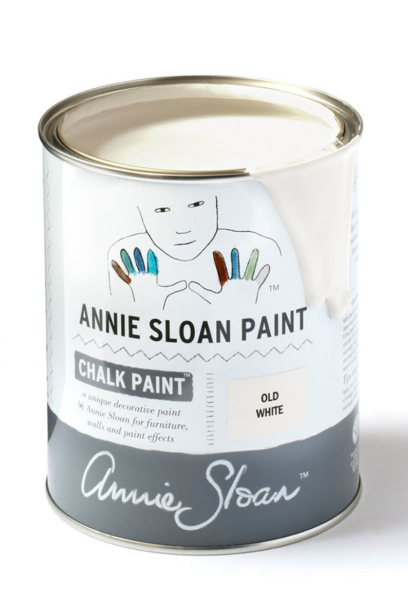 May include: A white can of Annie Sloan Chalk Paint in the color Old White. The can features a hand-painted illustration of a person with colorful hands and the brand name.
