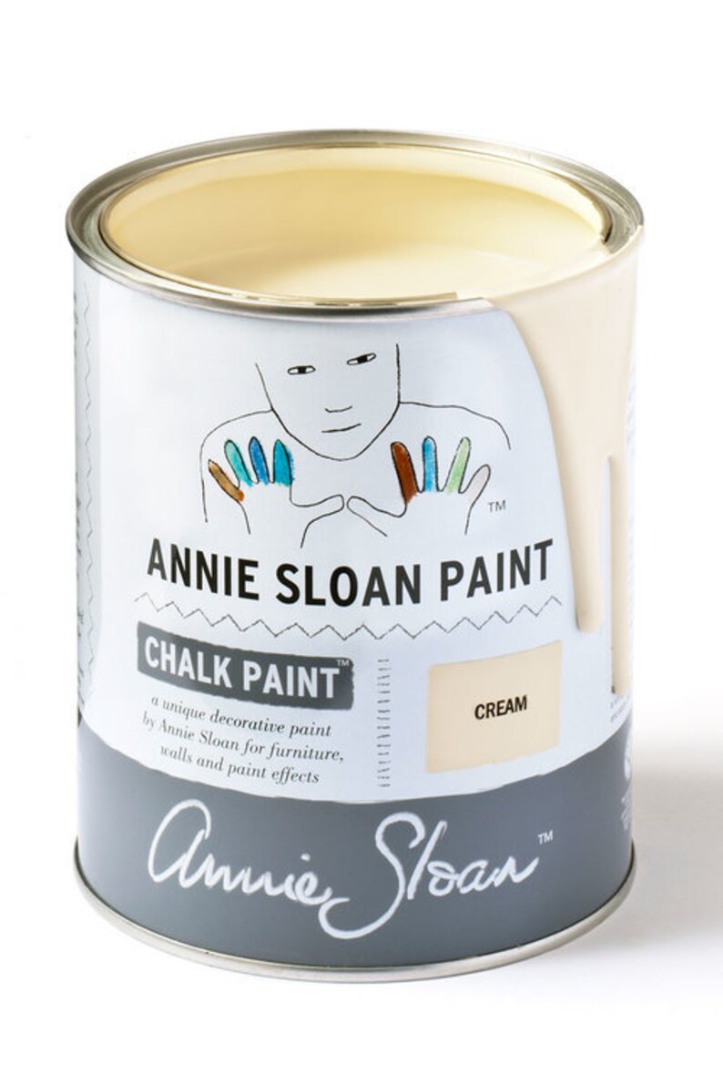 May include: A can of Annie Sloan Chalk Paint in the color Cream. The can is white with a gray label featuring a handprint design and the text "Annie Sloan Paint" and "Chalk Paint".
