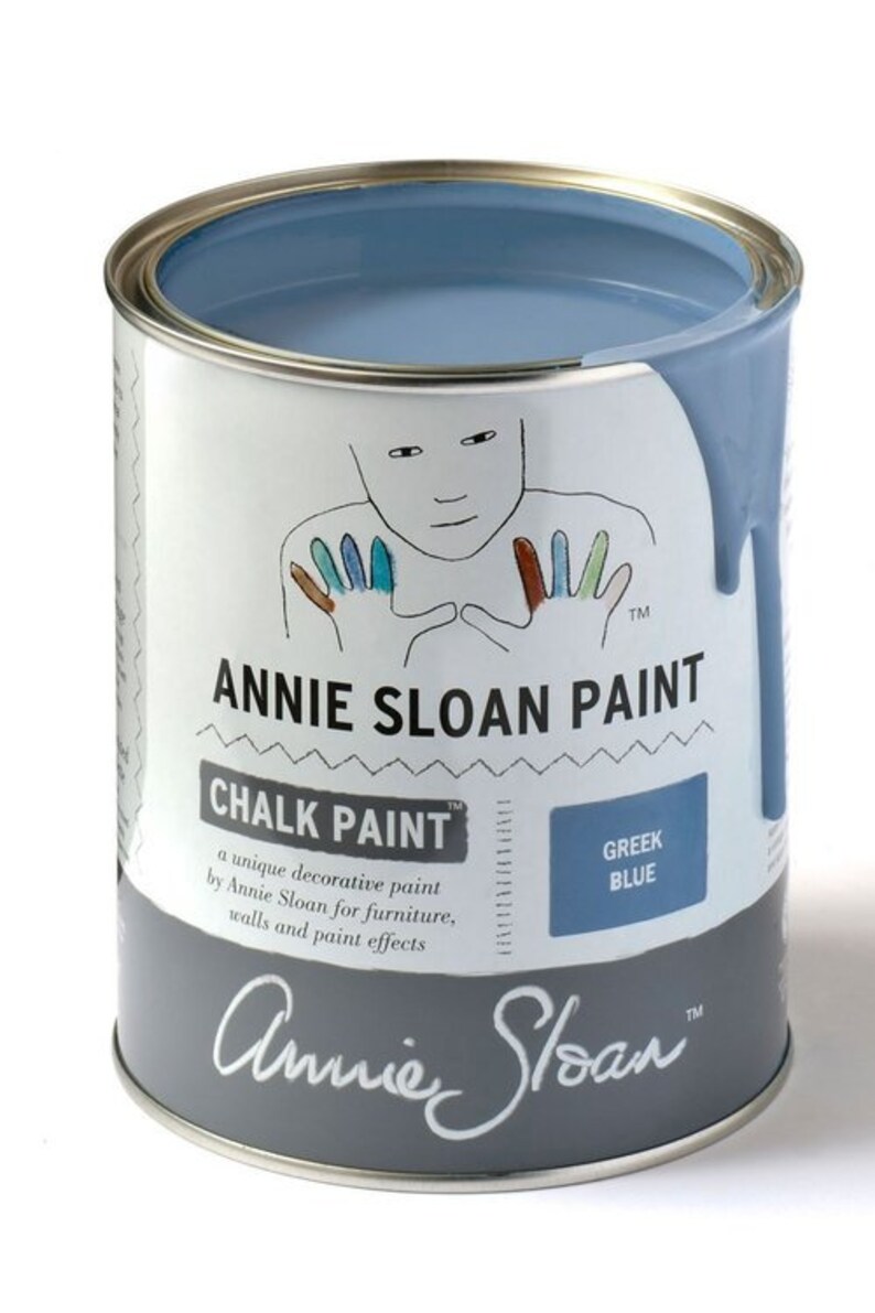 May include: A can of Annie Sloan Chalk Paint in the color Greek Blue. The can is open and the paint is spilling out. The label says "Annie Sloan Chalk Paint" and "Greek Blue".