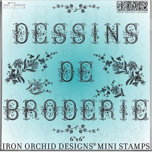 May include: A 6x6 inch Iron Orchid Designs mini stamp set featuring black floral-patterned letters spelling DESSINS DE BRODERIE. The design includes decorative botanical flourishes and the text The Painted Heirloom and Iron Orchid Designs.