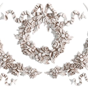 May include: A collection of ornate, off-white floral and ribbon decorative elements. The design includes a central wreath, corner pieces, and vertical floral accents, all with detailed textures and a classic aesthetic.
