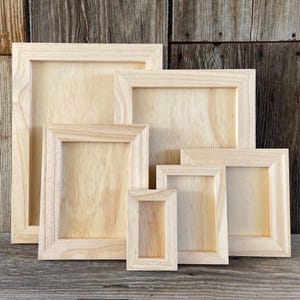 May include: Set of five unfinished wooden picture frames in various sizes. The frames are made of natural wood and have a smooth, unpainted surface.