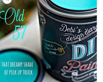 May include: A teal blue paint can with the text "Debi's design diary" and "DI Pain" on the label. The paint can is open and the paint is visible inside. The text "Old 57" is written on the left side of the image. The text "THAT DREAMY SHADE OF PICK UP TRUCK" is written below the paint can.
