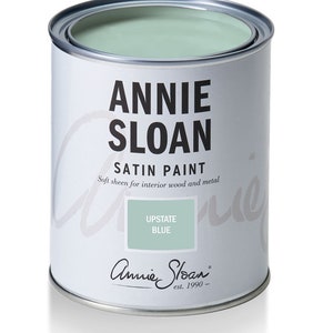 May include: A white paint can with a silver lid. The can is labeled "Annie Sloan Satin Paint" and "Upstate Blue". The label also says "Soft sheen for interior wood and metal" and "est. 1990".