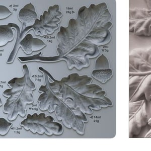 May include: A silicone mold for baking with a design of oak leaves and acorns. The mold is gray and has measurements in millimeters and grams.