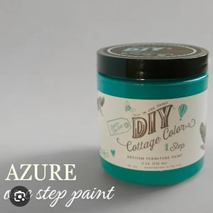 May include: A turquoise blue jar of DIY Cottage Color 1 Step Artisan Furniture Paint in the color Azure. The jar has a black lid and a white label with the brand name and product information.