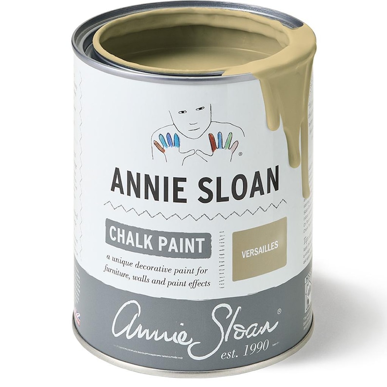 May include: A can of Annie Sloan Chalk Paint in the color Versailles. The paint is a light beige color and is shown with a small amount of paint dripping down the side of the can. The can has a white label with the Annie Sloan logo and the words "Chalk Paint" and "Versailles".