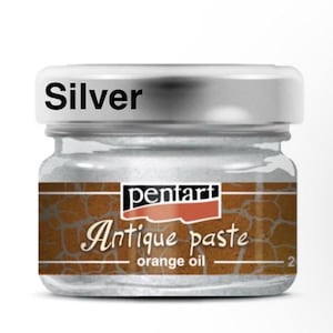May include: A small glass jar of silver-colored antique paste. The jar has a silver lid and a label with the brand name "pentart" and the words "Antique paste - orange oil". The word "Silver" is printed on the lid.