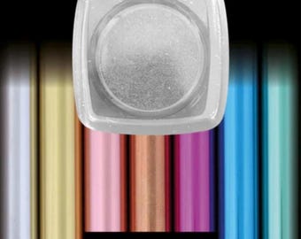 Puede incluir: Un recipiente cuadrado transparente lleno de purpurina plateada. El recipiente está encima de una fila de tubos metálicos de colores en tonos dorados, rosas, cobrizos, azules y turquesas. Una etiqueta negra debajo dice "SILVER".