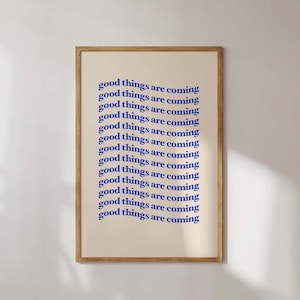 Könnte beinhalten: Ein beigefarbener gerahmter Druck mit dem Text "good things are coming", der in blauer Schrift wiederholt wird.