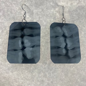 May include: A pair of silver earrings with black and white dental x-ray images.