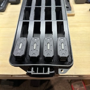 May include: A black plastic case with a foam insert for holding small electronic devices. Four black devices are in the case.