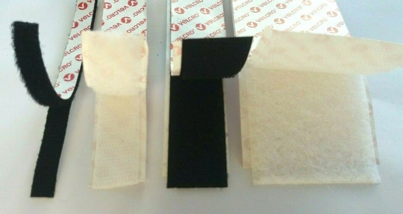 May include: Four strips of black hook and loop fastener tape with adhesive backing. The tape is labeled "VELCRO" and is shown with the adhesive backing exposed.