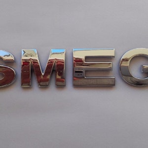 May include: A close-up of a silver metal logo that reads "SMEG".