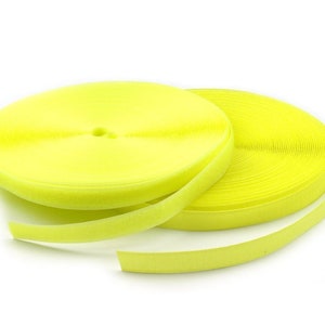 May include: A roll of bright yellow hook and loop fastener tape. The tape is rolled up and a section is unrolled, showing the soft, fuzzy texture.