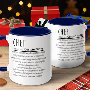 May include: White ceramic mug with a blue rim. The mug features a definition of the word "Chef" with the text "Custom name" in place of the definition. The mug is sitting on a wooden surface.